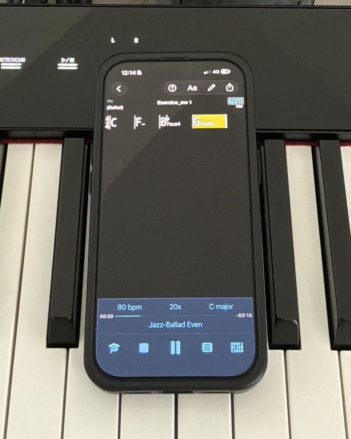 iReal Pro on an iPhone resting on a digital piano, playing a four-bar chord exercise as a jazz ballad at 80 bpm with 20 repeats queued and the current bar highlighted in yellow.